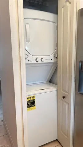 Laundry area featuring light tile patterned flooring and stacked washer and dryer