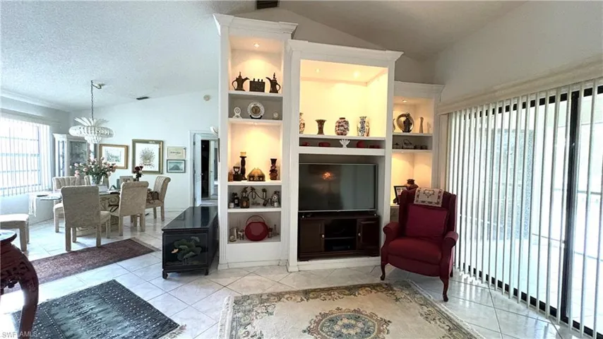 Living Room with view to the Dining area. Note the lighted, built-in shelving and sliding doors to the screened balcony.