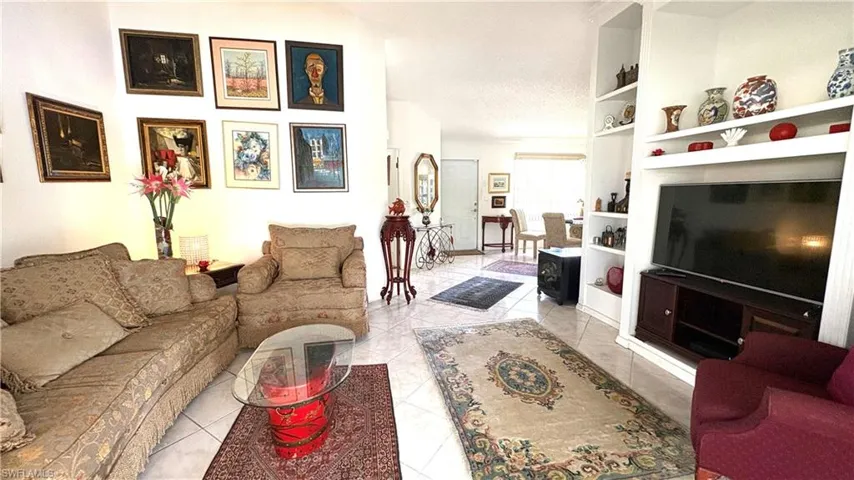 Living Room with view to Dining area and entry way has built-in lighted shelving and lofty, cathedral ceiling.