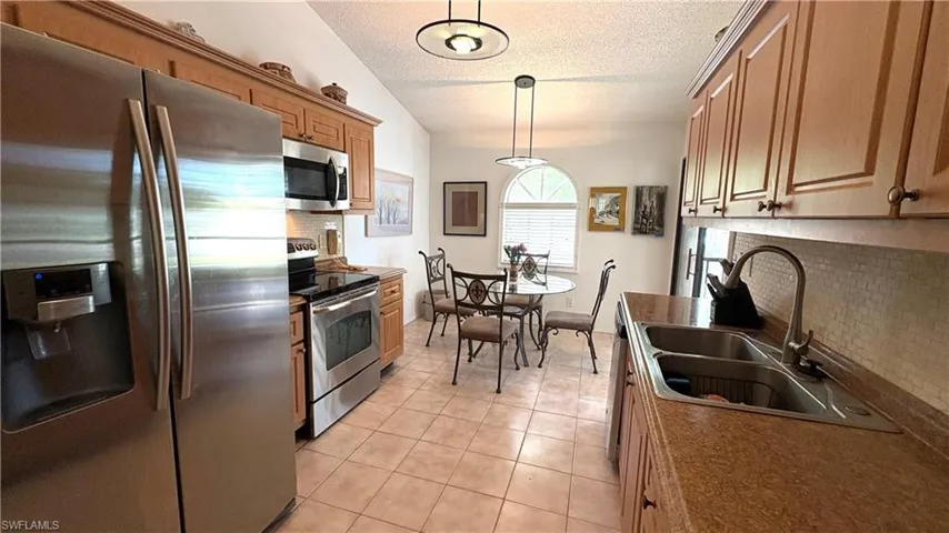 Your spacious Eat-in Kitchen features all NEWER stainless steel appliances, a textured ceiling, granite counters, light tile patterned floors, and decorative light fixtures.