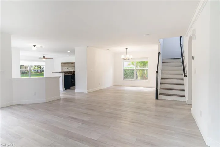 Unfurnished living room featuring a chandelier, ceiling fan, and light wood-style floors