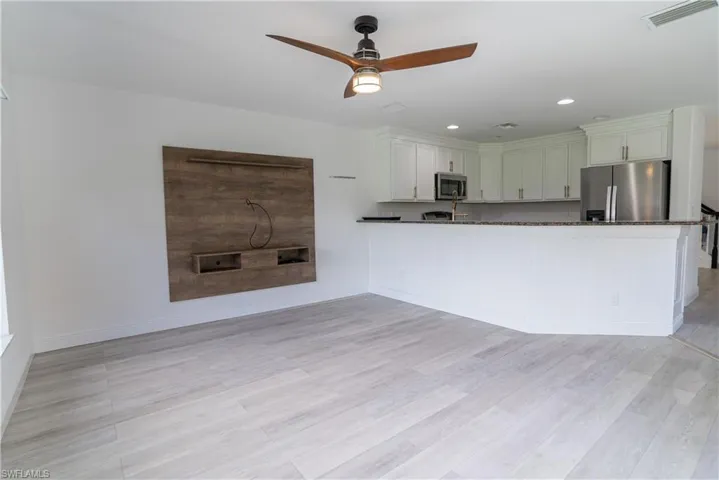 Kitchen with stainless steel appliances, ceiling fan, recessed lighting, light wood-style floors, and a peninsula