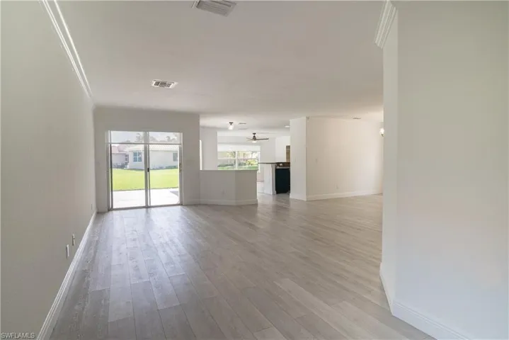 Unfurnished living room featuring light wood finished floors and ornamental molding