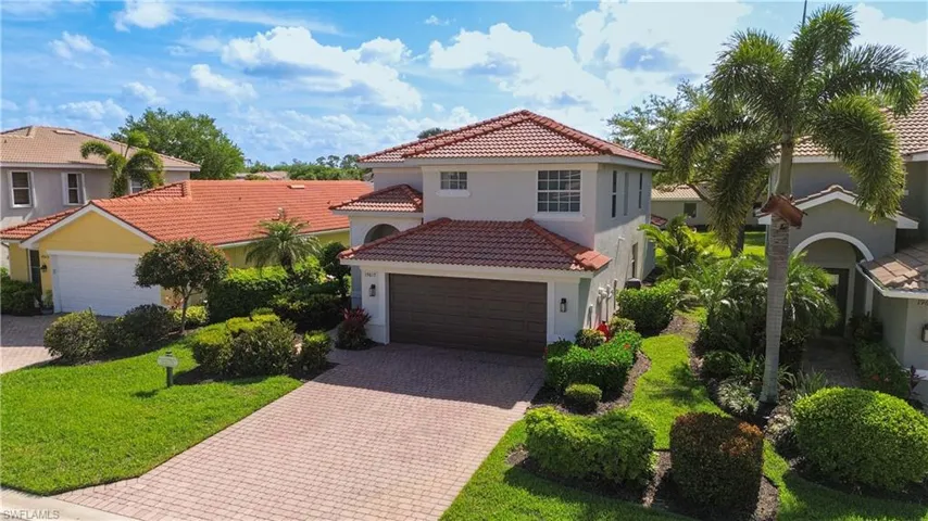 Mediterranean / spanish-style home with driveway, stucco siding, a tile roof, a garage, and a front lawn