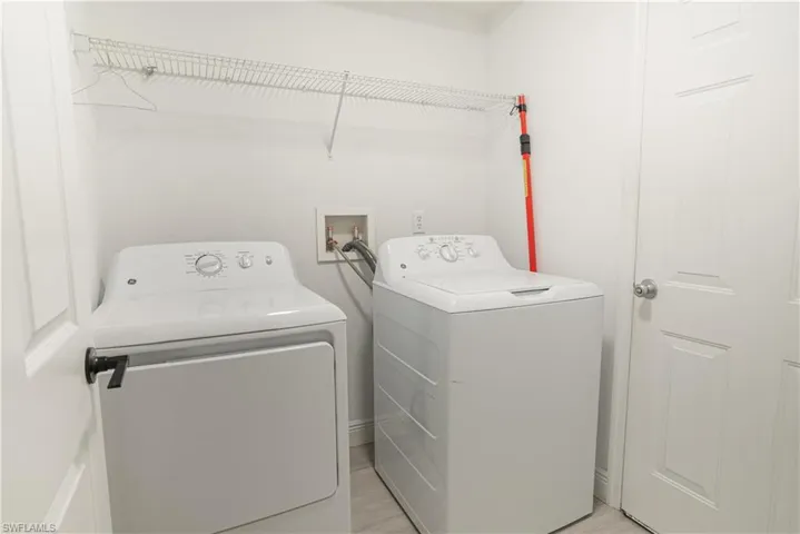 Laundry room with washing machine and clothes dryer and light wood-type flooring