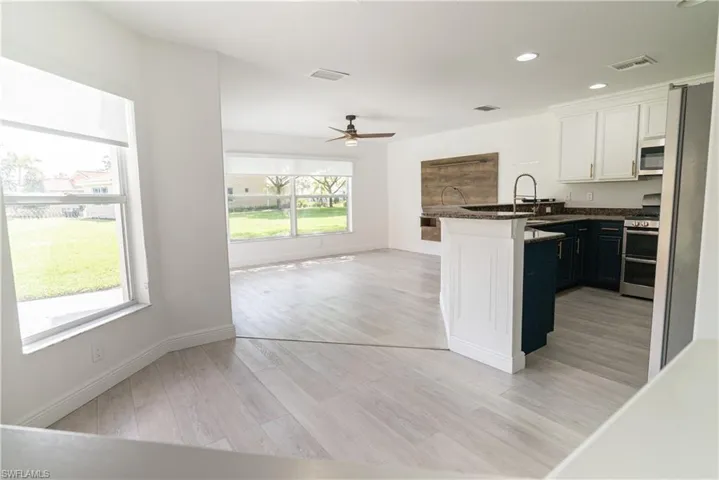 Kitchen featuring a peninsula, a ceiling fan, stainless steel appliances, light wood-type flooring, and two tone color scheme