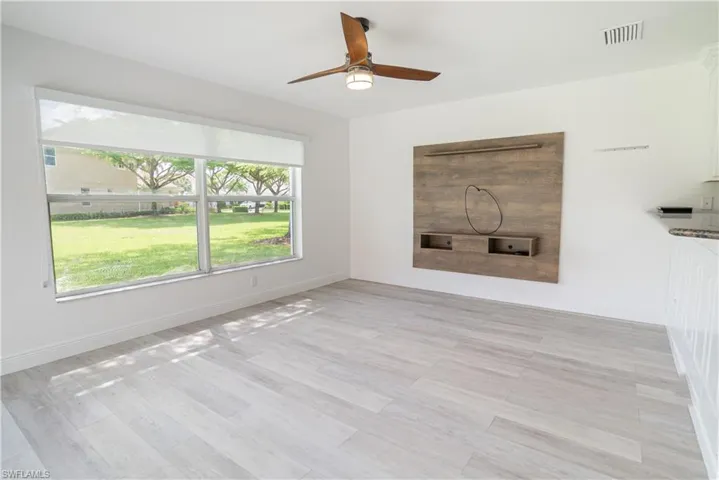 Unfurnished living room with ceiling fan and light wood-type flooring
