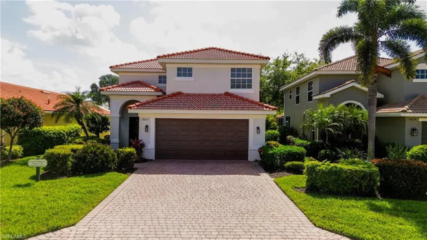 Mediterranean / spanish house with decorative driveway, a tile roof, stucco siding, and a front lawn