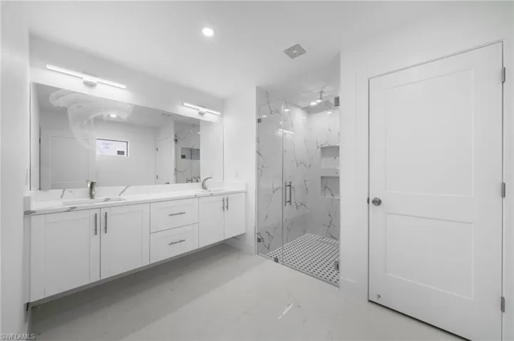 Bathroom with tile patterned flooring, an enclosed shower, and dual bowl vanity