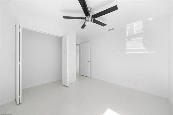 Unfurnished bedroom featuring a closet, light tile patterned floors, and ceiling fan