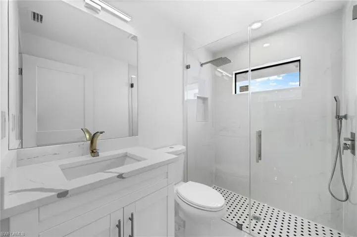 Bathroom with a shower with door, toilet, and vanity
