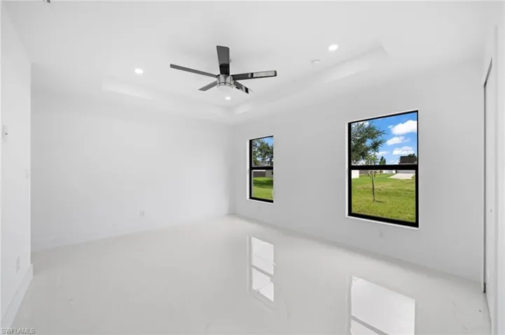 Tiled spare room with ceiling fan and a tray ceiling