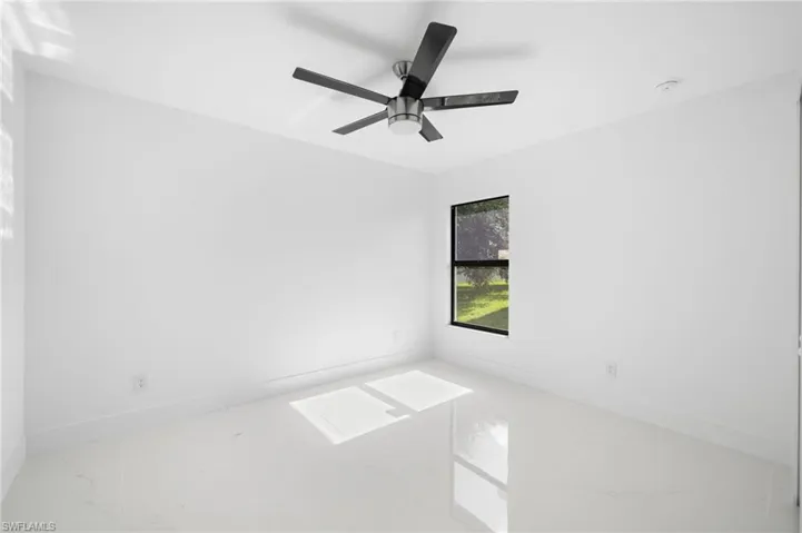 Empty room featuring ceiling fan and tile patterned floors