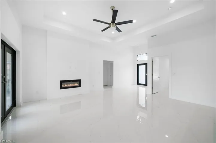 Unfurnished living room with light tile patterned floors, a raised ceiling, and ceiling fan