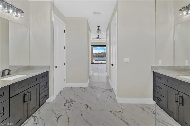 Bathroom featuring vanity, light marble finish flooring, and ceiling fan