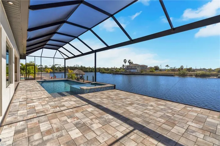 Integrated pool / hot tub featuring a sunroom, a lanai, a patio area, and a water view
