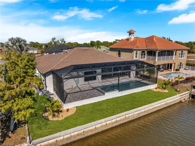 Rear view of property with an outdoor pool, a yard, a tiled roof, a water view, and glass enclosure