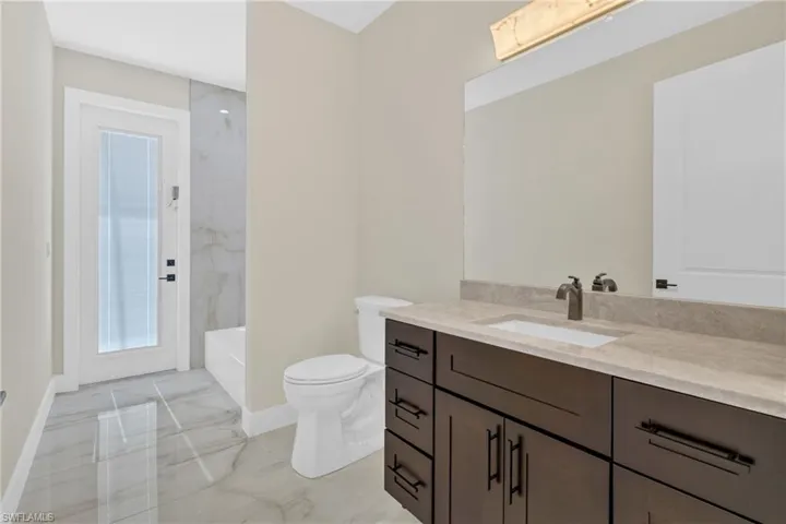 Full bathroom featuring light marble finish floors, vanity, and shower / bath combination
