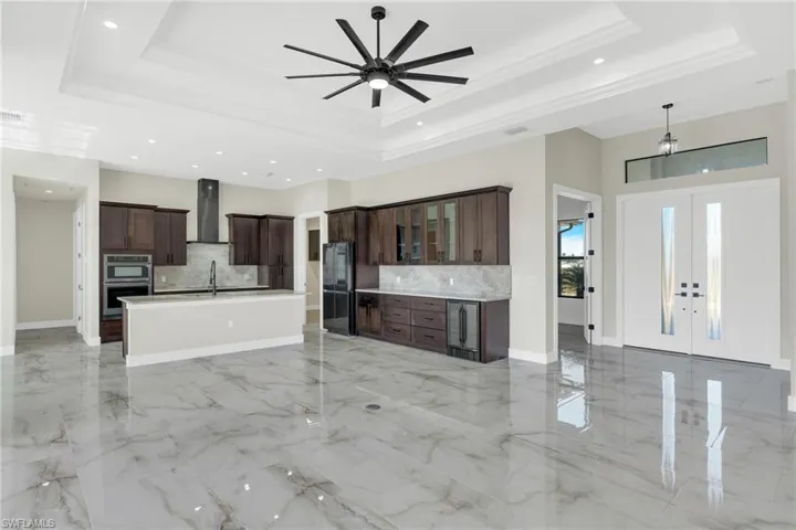 Kitchen with open floor plan, glass insert cabinets, a ceiling fan, french doors, and smart refrigerator