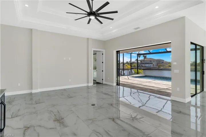 Spare room featuring a sunroom, a ceiling fan, a water view, light marble finish floors, and recessed lighting