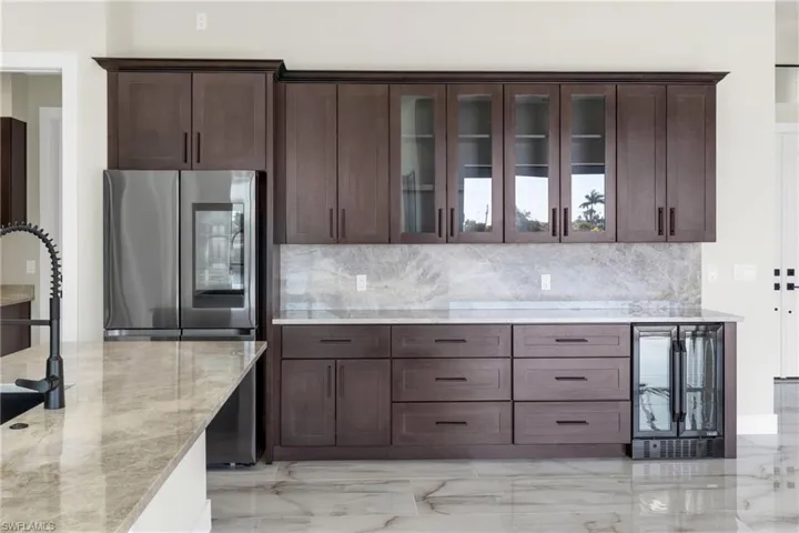Kitchen with smart refrigerator, wine cooler, glass insert cabinets, and light stone counters