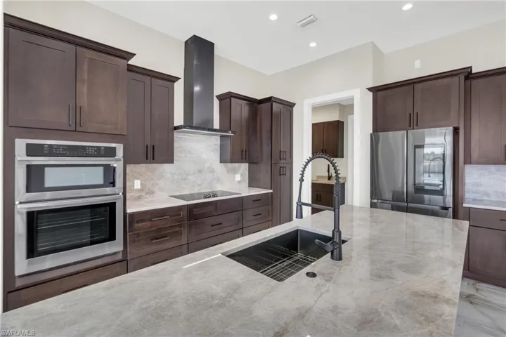 Kitchen featuring decorative backsplash, stainless steel appliances, dark wood finish cabinetry, and recessed lighting