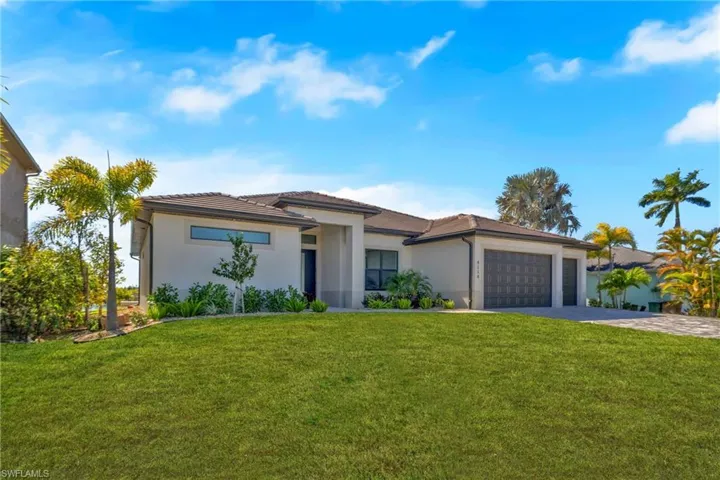Prairie-style house with a front lawn, stucco siding, and driveway