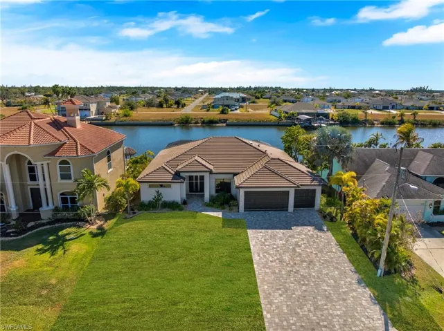 View of front of house featuring a residential view, decorative driveway, stucco siding, a garage, and a water view
