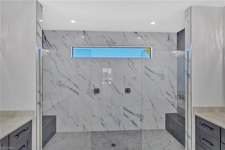 Full bath with vanity, healthy amount of natural light, a marble finish shower, and recessed lighting