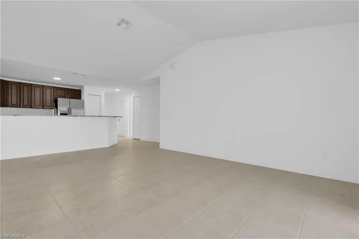 Unfurnished living room featuring light tile patterned flooring, vaulted ceiling, and recessed lighting