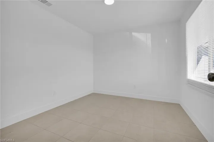 Empty room with light tile patterned flooring and lofted ceiling