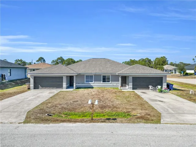 Ranch-style home with an attached garage, driveway, a shingled roof, and stucco siding
