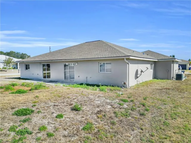 Back of property featuring a shingled roof and stucco siding