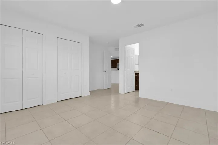 Unfurnished bedroom featuring multiple closets, light tile patterned floors, and connected bathroom