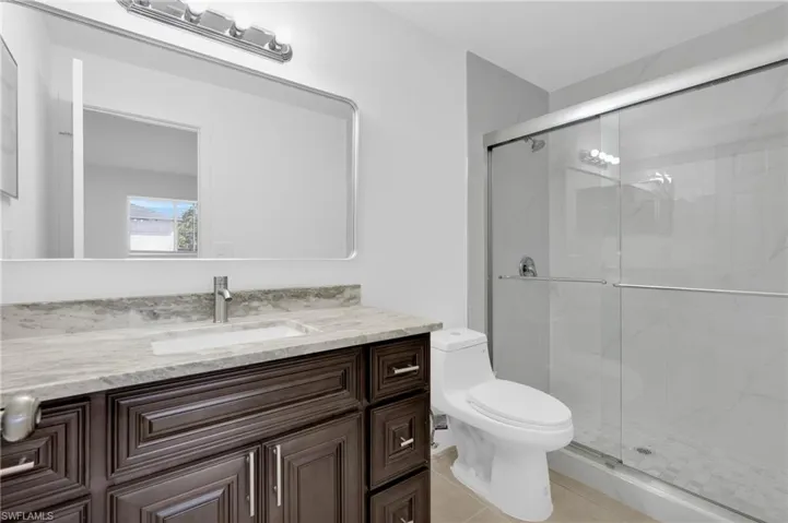 Full bath featuring vanity, a marble finish shower, and light tile patterned floors