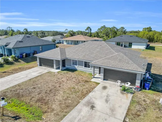 Ranch-style house with roof with shingles, a garage, driveway, and a front lawn