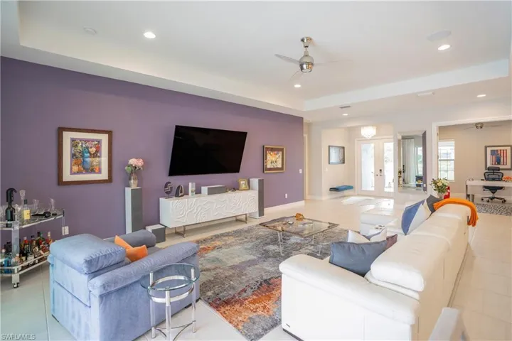Living room featuring ceiling fan, light tile patterned flooring, and french doors