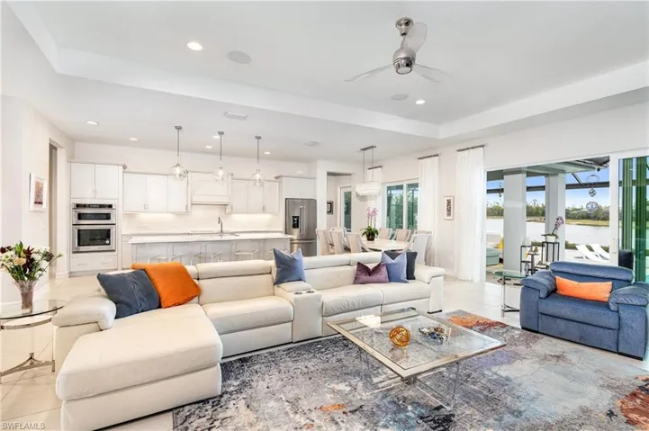 Living room featuring ceiling fan, light tile patterned floors, a tray ceiling, and sink
