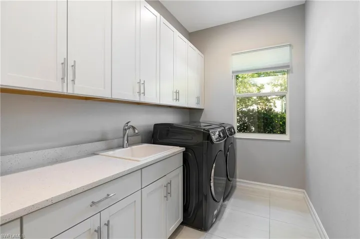 Laundry area featuring washer and dryer, cabinets, and sink
