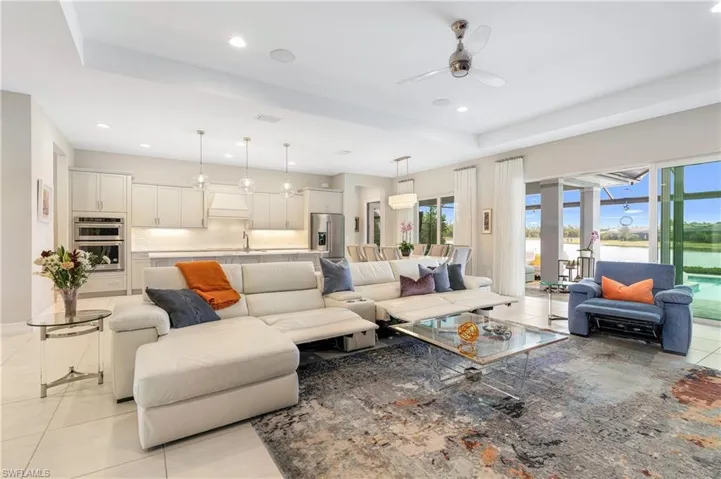 Living room featuring ceiling fan, light tile patterned floors, and a tray ceiling