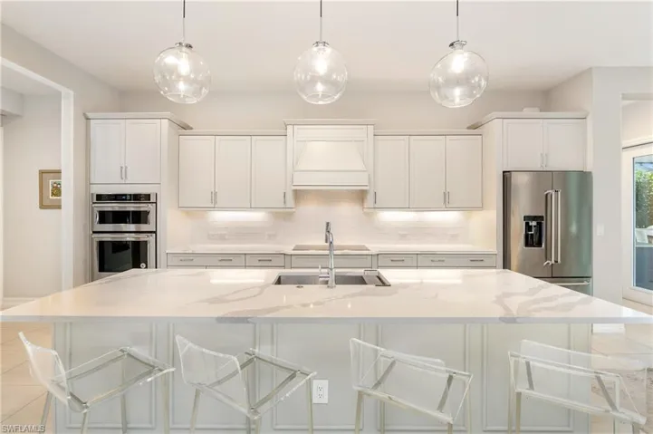 Kitchen featuring decorative light fixtures, white cabinets, and appliances with stainless steel finishes