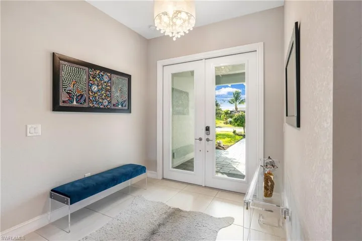 Doorway with french doors, light tile patterned floors, and a notable chandelier