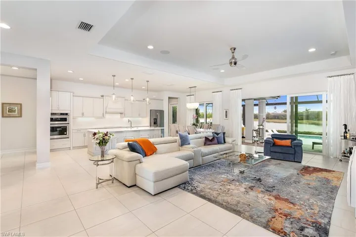 Living room featuring ceiling fan, light tile patterned flooring, a raised ceiling, and sink