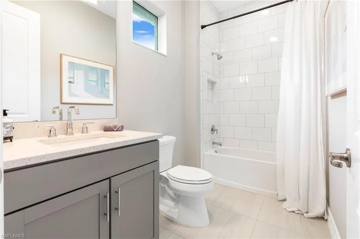 Full bathroom featuring toilet, tile patterned flooring, shower / bath combination with curtain, and vanity