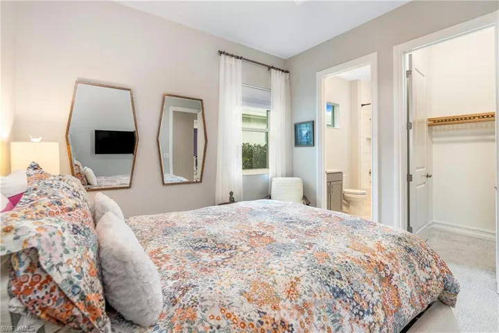 Bedroom featuring a closet, ensuite bathroom, carpet, and a walk in closet
