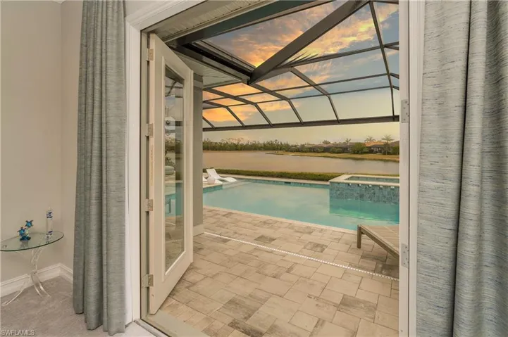 Pool at dusk with a patio, an in ground hot tub, a water view, and a lanai