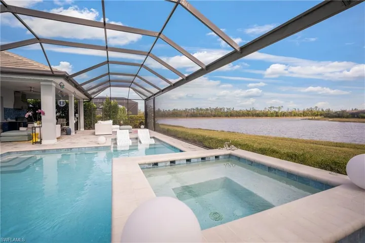 View of pool with a water view, a patio, an in ground hot tub, and a lanai