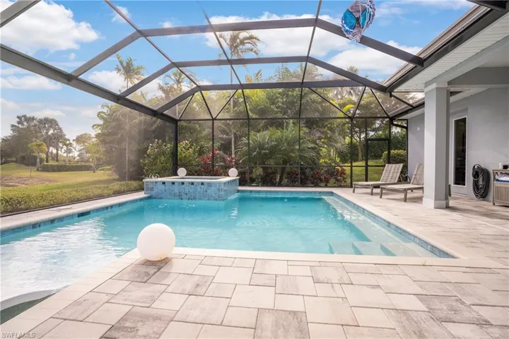 View of swimming pool with glass enclosure and a patio area