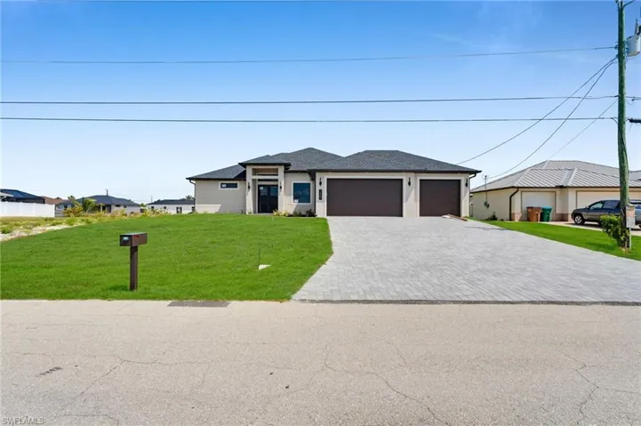 Prairie-style house featuring an attached garage, decorative driveway, and a front lawn
