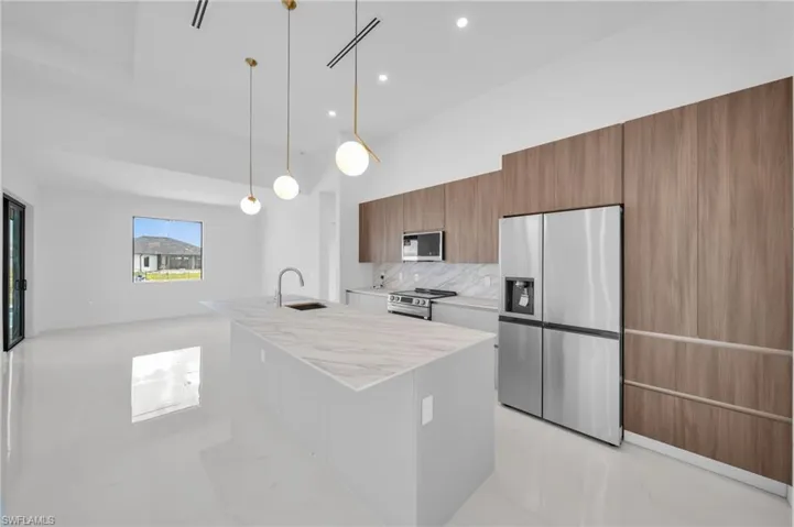Kitchen with a sink, modern cabinets, brown cabinets, light countertops, and appliances with stainless steel finishes
